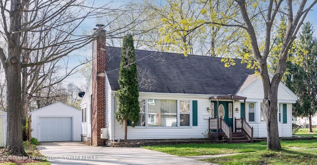 cape cod house with a shingled roof, a garage, an outbuilding, a chimney, and concrete driveway