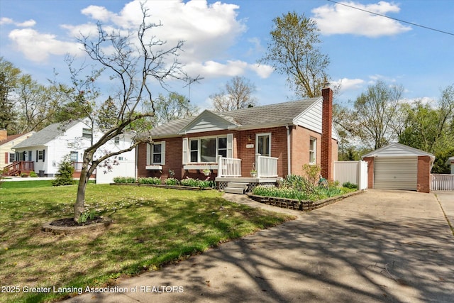 view of front facade featuring brick siding, a front yard, an outbuilding, a chimney, and concrete driveway