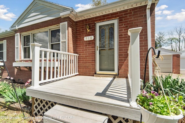 entrance to property featuring brick siding and a deck