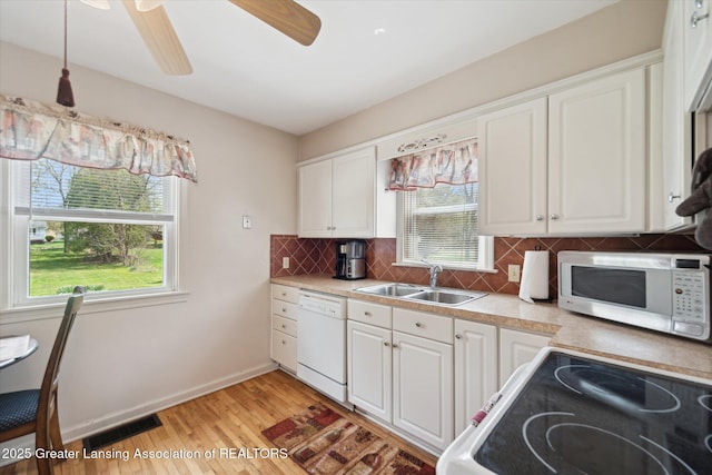 kitchen featuring visible vents, a sink, a wealth of natural light, and white appliances