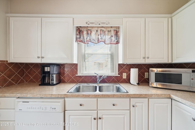 kitchen featuring white dishwasher, white cabinets, stainless steel microwave, and a sink