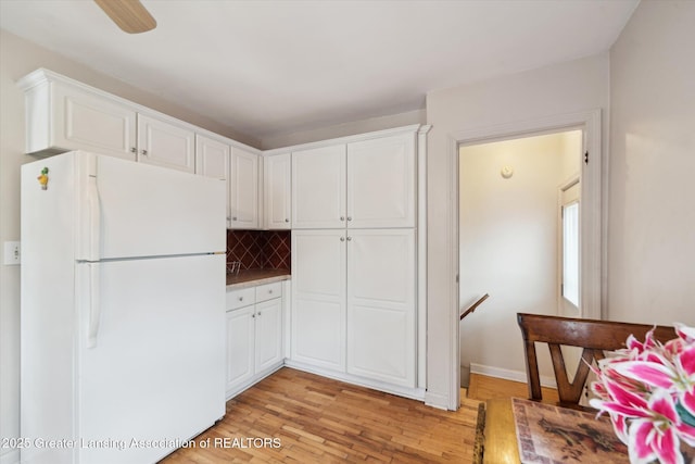 kitchen with freestanding refrigerator, light wood-style flooring, backsplash, and white cabinets