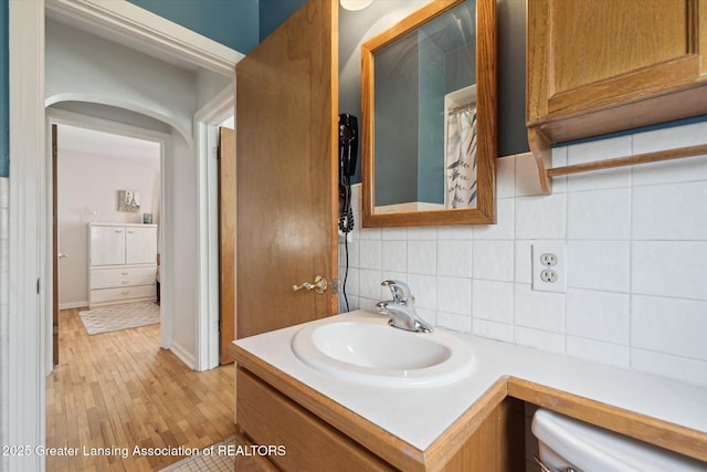 bathroom with wood finished floors, baseboards, backsplash, and vanity