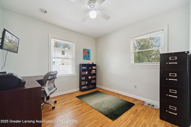 office featuring light wood-style floors, baseboards, a healthy amount of sunlight, and visible vents