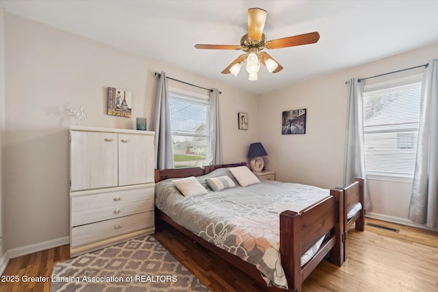 bedroom with baseboards, ceiling fan, light wood-style flooring, and visible vents