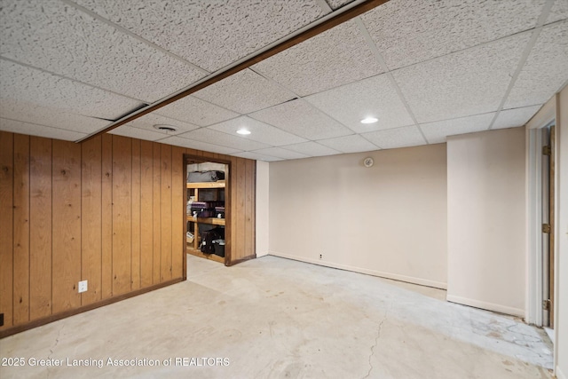 finished basement with baseboards, wood walls, a paneled ceiling, and recessed lighting
