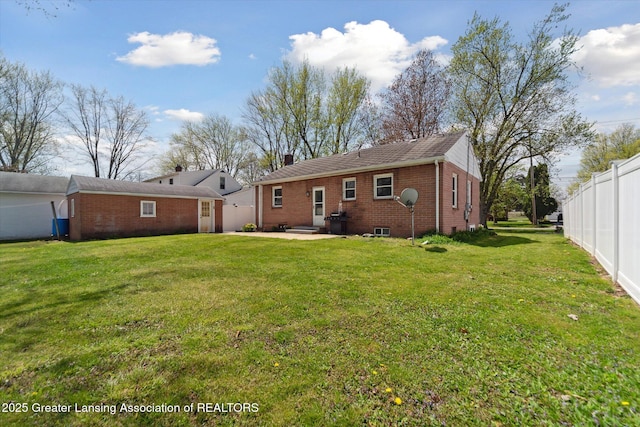 back of property with a chimney, a patio area, brick siding, fence, and a yard