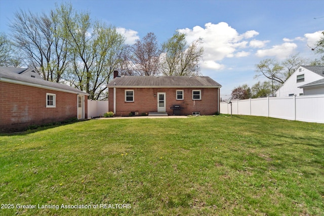 back of property with fence, a chimney, a lawn, and brick siding