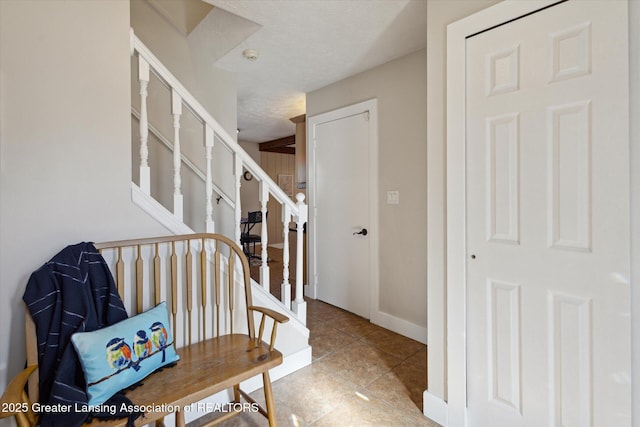 stairway with a textured ceiling, baseboards, and tile patterned flooring