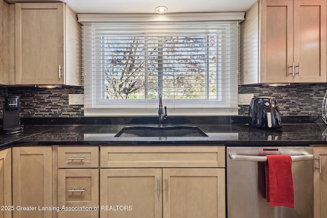 kitchen featuring stainless steel dishwasher, a sink, light brown cabinets, and tasteful backsplash