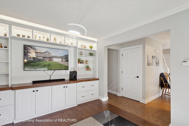 living room with crown molding, a textured ceiling, baseboards, and dark wood-type flooring