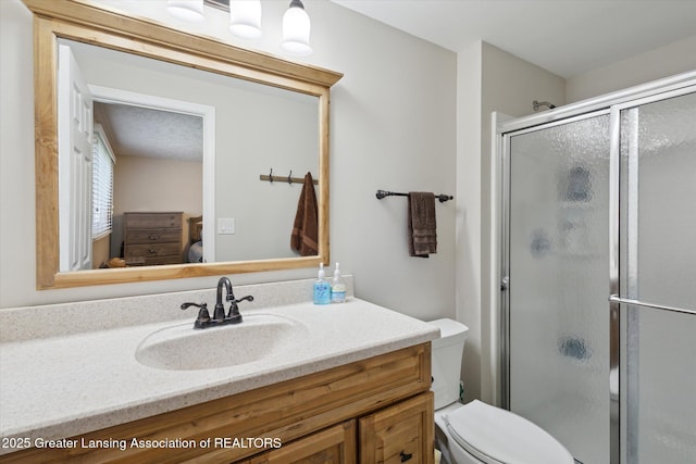 ensuite bathroom featuring ensuite bathroom, a stall shower, toilet, and vanity