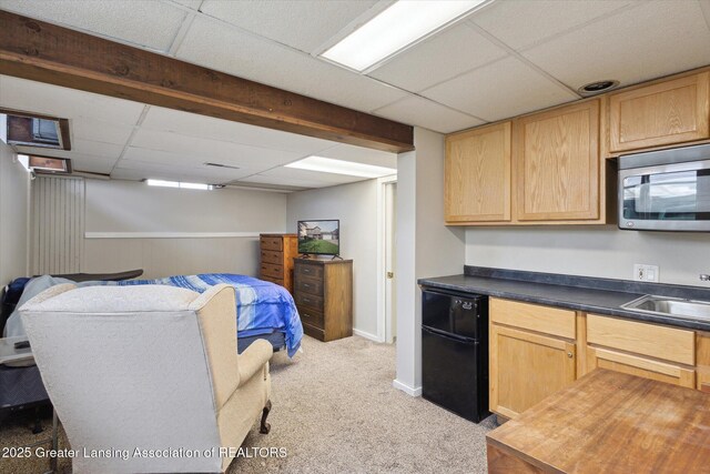 interior space featuring light colored carpet, a sink, baseboards, a drop ceiling, and refrigerator