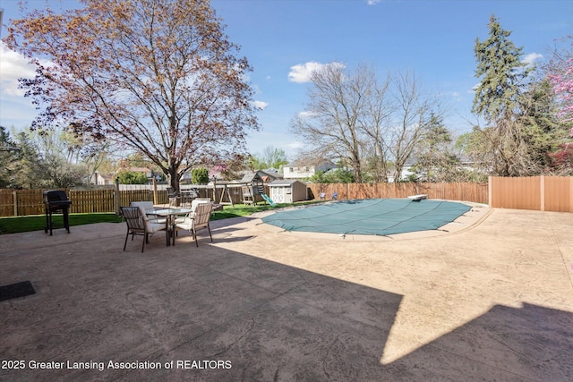 view of pool featuring a fenced backyard, a storage unit, a patio, and a fenced in pool
