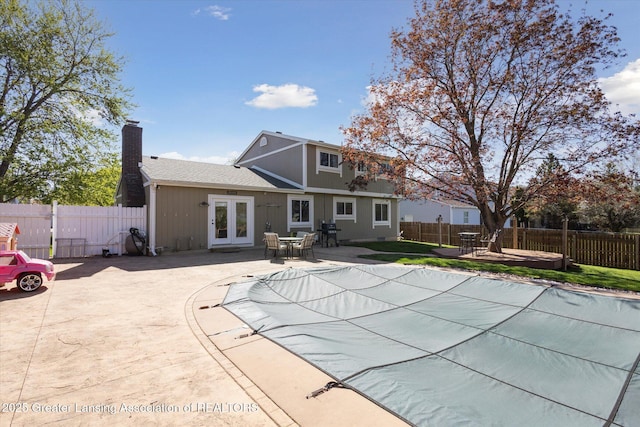 view of swimming pool featuring a fenced in pool, a fenced backyard, french doors, and a patio