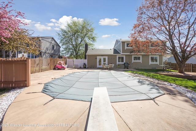 view of pool with a deck, a fenced in pool, a fenced backyard, a patio area, and french doors