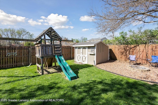 view of jungle gym with a lawn, a fenced backyard, a shed, and an outbuilding