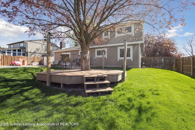 rear view of house featuring a lawn, a wooden deck, and a fenced backyard