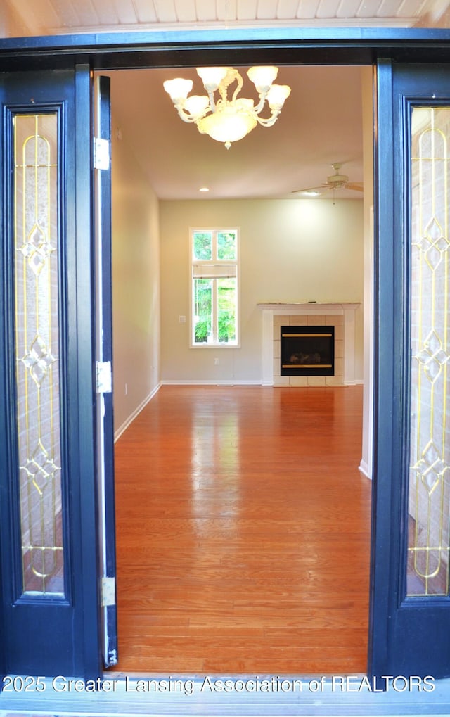 3401 N Burwick Dr, Port Huron, MI 48060 - unfurnished living room with wood finished floors, a chandelier, baseboards, a tile fireplace, and ceiling fan