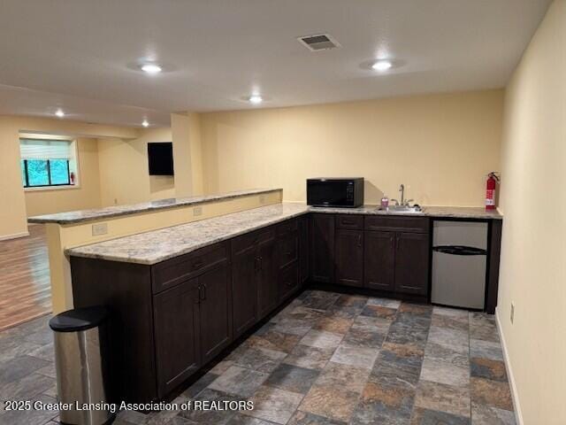 2434 Emerald Lake Dr, East Lansing, MI 48823 - kitchen with black microwave, fridge, a peninsula, dark stone finish floors, and recessed lighting