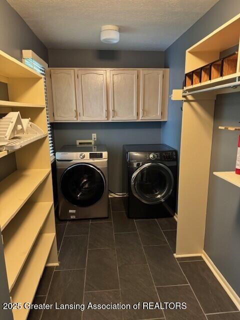 2434 Emerald Lake Dr, East Lansing, MI 48823 - laundry room with independent washer and dryer, a textured ceiling, cabinet space, and dark tile patterned floors