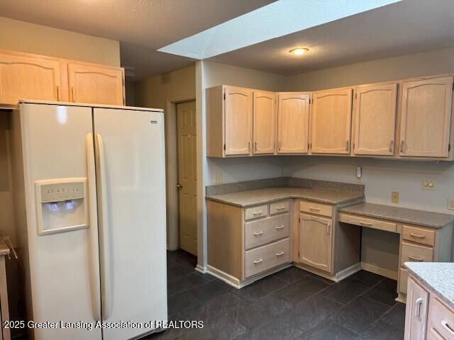 2434 Emerald Lake Dr, East Lansing, MI 48823 - kitchen with white refrigerator with ice dispenser, light countertops, light brown cabinets, built in study area, and dark tile patterned floors