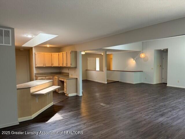 2434 Emerald Lake Dr, East Lansing, MI 48823 - kitchen with open floor plan, dark wood finished floors, light brown cabinets, light countertops, and a skylight