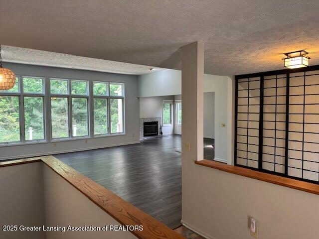 2434 Emerald Lake Dr, East Lansing, MI 48823 - unfurnished living room with a textured ceiling, healthy amount of natural light, a glass covered fireplace, and wood finished floors
