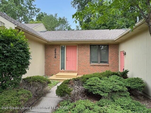 2434 Emerald Lake Dr, East Lansing, MI 48823 - view of exterior entry featuring brick siding and a shingled roof