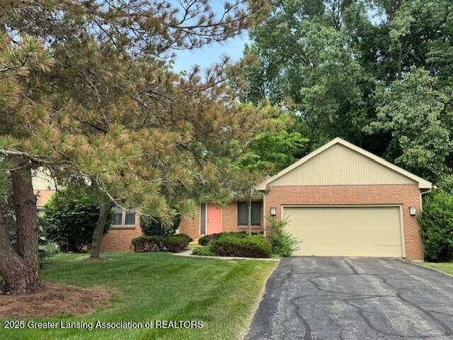 2434 Emerald Lake Dr, East Lansing, MI 48823 - view of front of property with asphalt driveway, a garage, brick siding, and a front yard