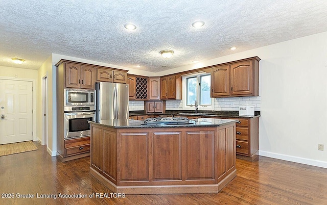 8505 W Willow Hwy, Grand Ledge, MI 48837 - kitchen with appliances with stainless steel finishes, baseboards, dark wood-type flooring, tasteful backsplash, and a textured ceiling