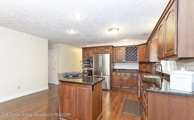 8505 W Willow Hwy, Grand Ledge, MI 48837 - kitchen with stainless steel appliances, a sink, dark wood-type flooring, baseboards, and a textured ceiling