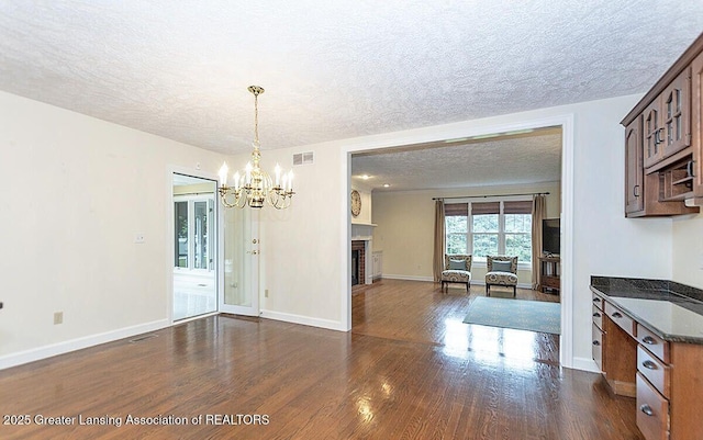 8505 W Willow Hwy, Grand Ledge, MI 48837 - dining area with a textured ceiling, a chandelier, dark wood-style floors, a fireplace, and baseboards