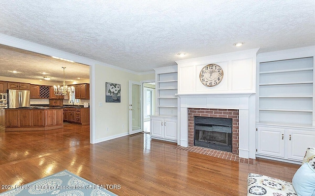 8505 W Willow Hwy, Grand Ledge, MI 48837 - unfurnished living room featuring a textured ceiling, dark wood-style floors, baseboards, a fireplace, and a chandelier