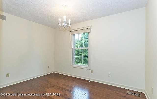 8505 W Willow Hwy, Grand Ledge, MI 48837 - unfurnished room with a chandelier, dark wood-style floors, a textured ceiling, and baseboards