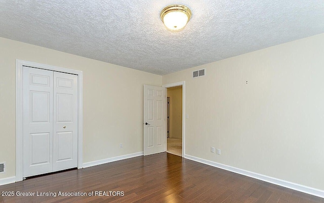 8505 W Willow Hwy, Grand Ledge, MI 48837 - unfurnished bedroom with dark wood-style flooring, a closet, baseboards, and a textured ceiling