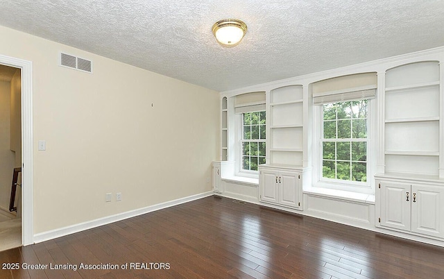 8505 W Willow Hwy, Grand Ledge, MI 48837 - spare room with dark wood-style flooring, a textured ceiling, built in shelves, plenty of natural light, and baseboards