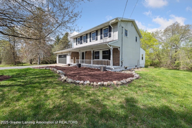 view of front facade featuring an attached garage, brick siding, a front yard, covered porch, and driveway