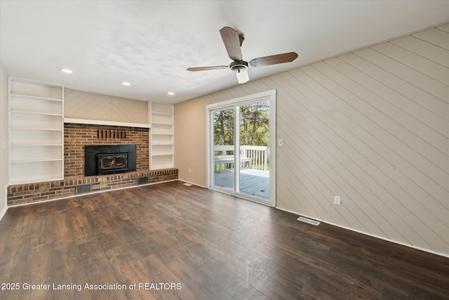 unfurnished living room featuring a ceiling fan, visible vents, built in features, wood finished floors, and baseboards