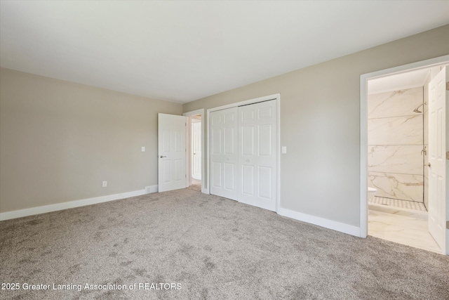 unfurnished bedroom featuring baseboards, ensuite bathroom, carpet, and a closet