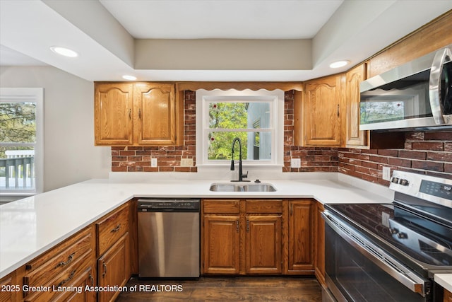 kitchen featuring appliances with stainless steel finishes, tasteful backsplash, brown cabinets, a sink, and light countertops