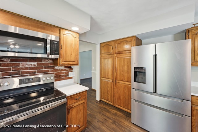 kitchen featuring light countertops, brown cabinets, stainless steel appliances, and dark wood finished floors