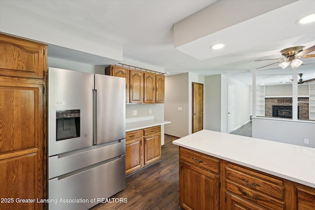 kitchen featuring ceiling fan, brown cabinetry, light countertops, stainless steel fridge with ice dispenser, and dark wood-style floors