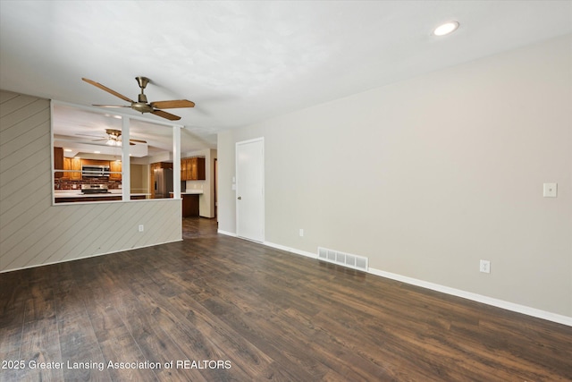 unfurnished living room featuring baseboards, ceiling fan, visible vents, and dark wood finished floors