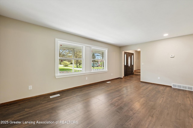 unfurnished living room with baseboards, dark wood-style flooring, and visible vents