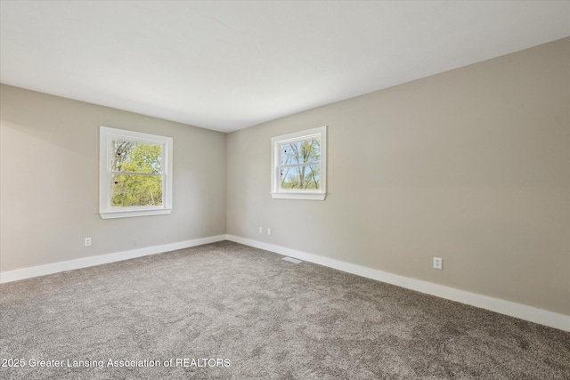 spare room with carpet floors, baseboards, and visible vents