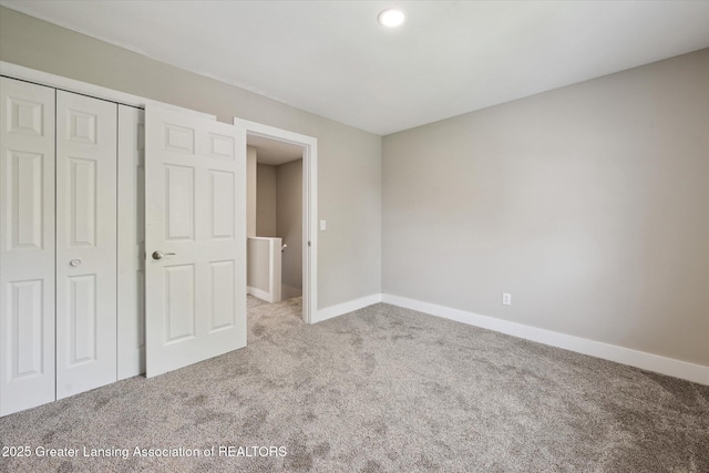 unfurnished bedroom with carpet floors, baseboards, and a closet