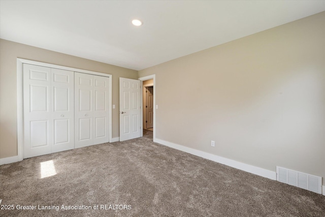 unfurnished bedroom featuring baseboards, carpet, a closet, and visible vents