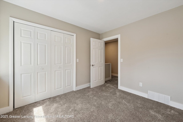 unfurnished bedroom featuring visible vents, carpet, baseboards, and a closet
