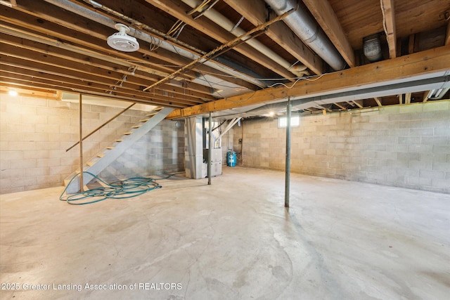 unfinished below grade area featuring heating unit and stairway